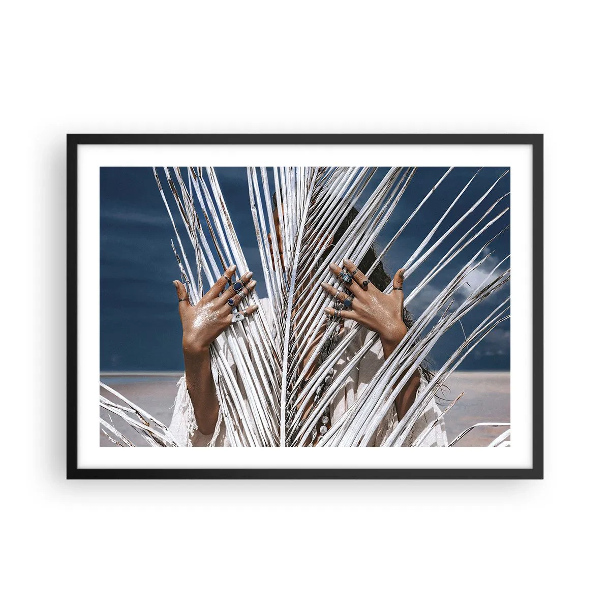 Affiche dans un cadre noir - Poster - Une femme cachée derrière des feuilles de palmier avec des bagues aux mains. - 70x50cm - Fille de chaman ? - Décoration murale moderne pour le salon et la chambre ARTTOR