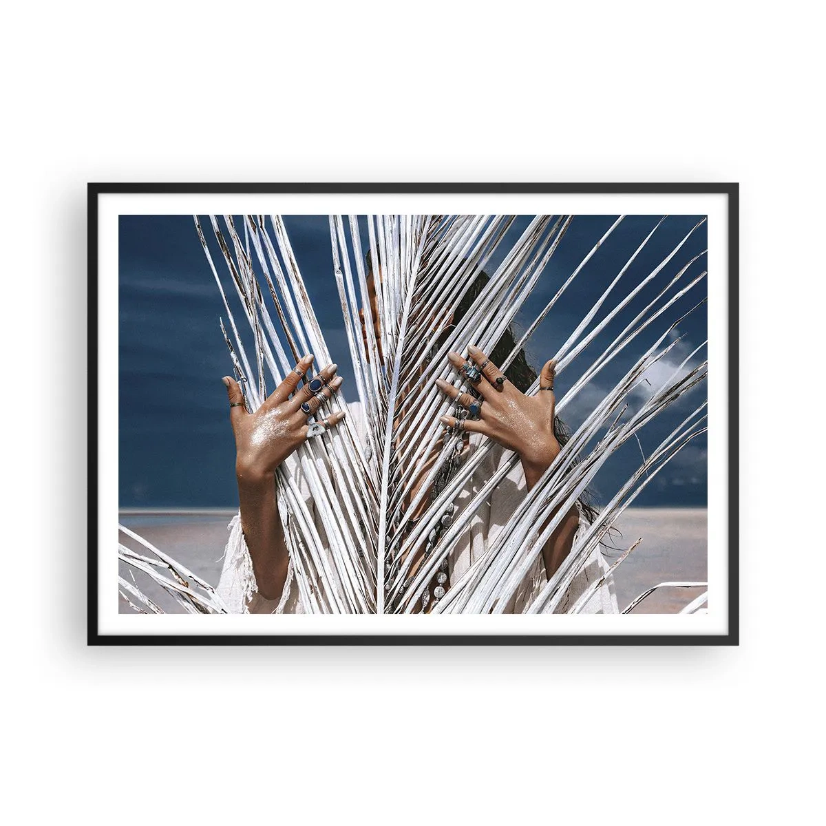 Affiche dans un cadre noir - Poster - Une femme cachée derrière des feuilles de palmier avec des bagues aux mains. - 100x70cm - Fille de chaman ? - Décoration murale moderne pour le salon et la chambre ARTTOR