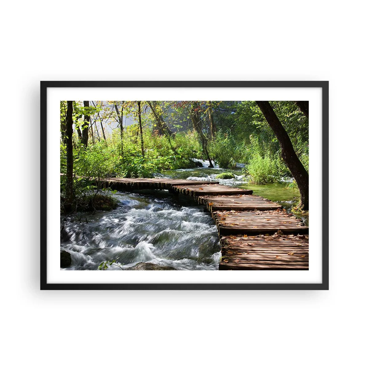 Affiche dans un cadre noir - Poster - Un pont en bois sur un ruisseau tumultueux entouré par la verdure de la forêt. - 70x50cm - Au-dessus de la cascade mousseuse - Décoration murale moderne pour le salon et la chambre ARTTOR