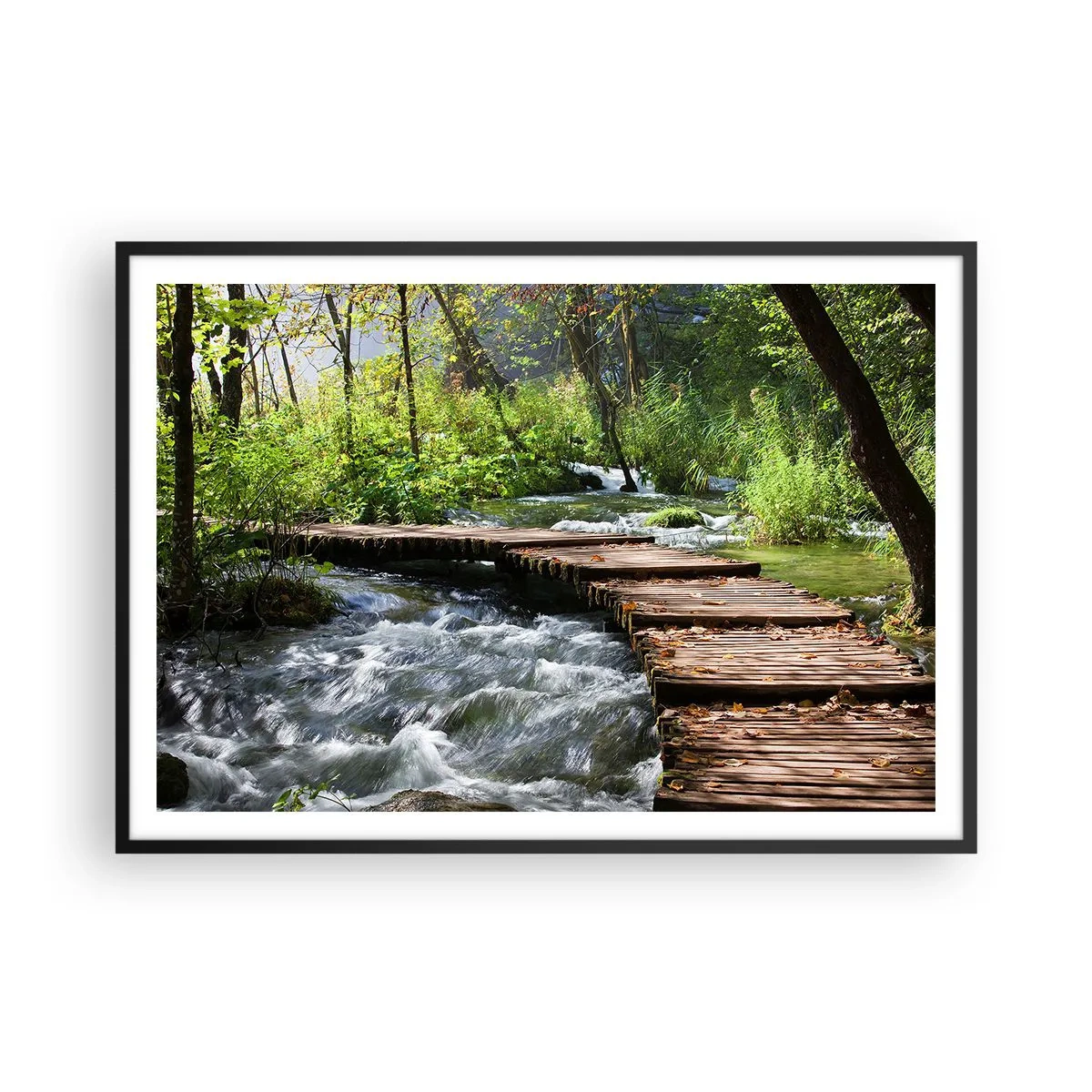 Affiche dans un cadre noir - Poster - Un pont en bois sur un ruisseau tumultueux entouré par la verdure de la forêt. - 100x70cm - Au-dessus de la cascade mousseuse - Décoration murale moderne pour le salon et la chambre ARTTOR