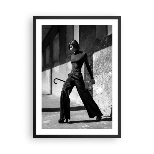 Affiche dans un cadre noir - Poster - Une femme dans une tenue élégante avec une canne sur fond d'architecture austère - 50x70cm - Élégance urbaine - Décoration murale moderne pour le salon et la chambre ARTTOR