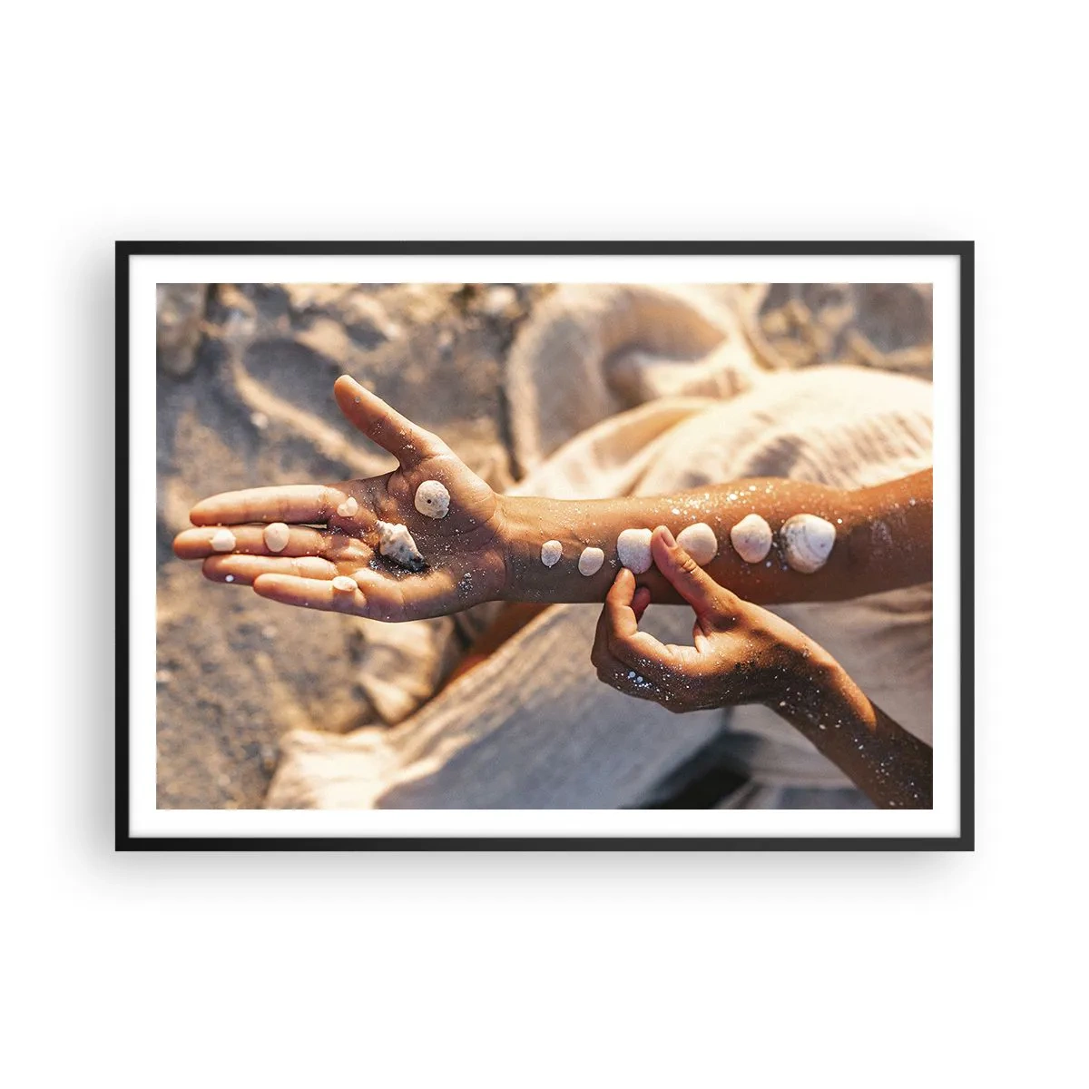 Affiche dans un cadre noir - Poster - Mains avec des coquillages disposés sur le fond de sable - 100x70cm - La beauté à portée de main - Décoration murale moderne pour le salon et la chambre ARTTOR